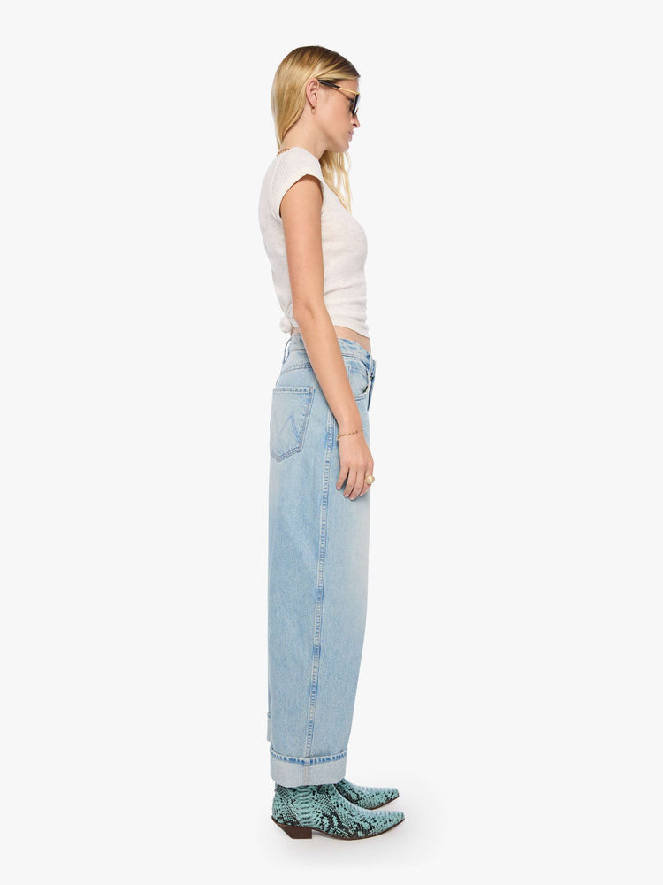 Side view of a woman in a light blue jeans designed to sit lower on the hips with an ankle-length inseam, zip fly, tacked, folded hem and a slightly tapered leg. 