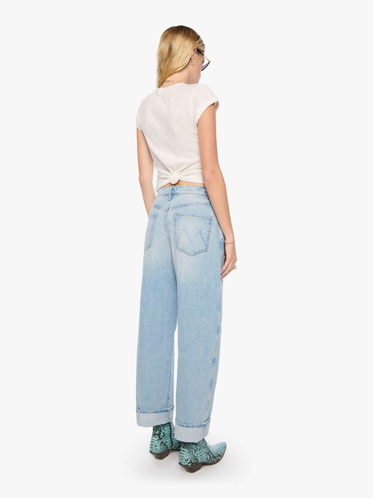 Back view of a woman in a light blue jeans designed to sit lower on the hips with an ankle-length inseam, zip fly, tacked, folded hem and a slightly tapered leg. 