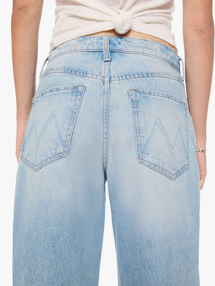 Back close up view of a woman in a light blue jeans designed to sit lower on the hips with an ankle-length inseam, zip fly, tacked, folded hem and a slightly tapered leg. 