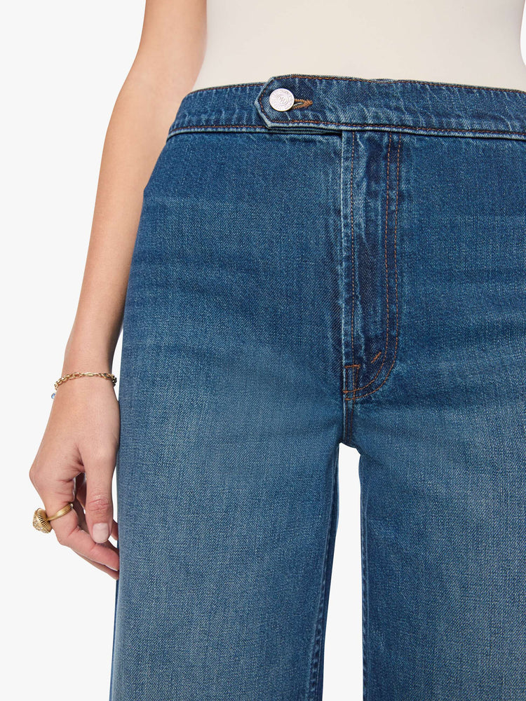 Close up view of a woman in med blue high-rise wide-leg jeans with a zip fly, button-tab waistband, a long 32-inch inseam and a loose, low-slung fit. 