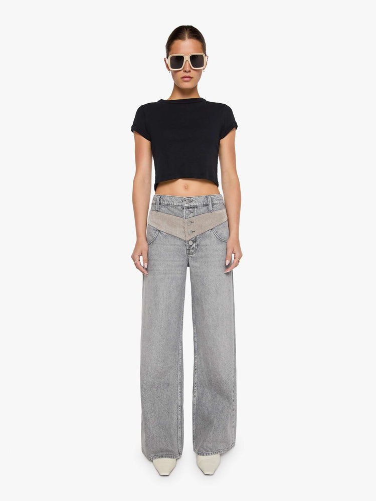 Front view of a woman in a washed grey high-rise pants are designed with an inset corduroy panel at the waist and down the back legs, an exposed button fly, low-slung fit and a 30-inch inseam with a clean hem.