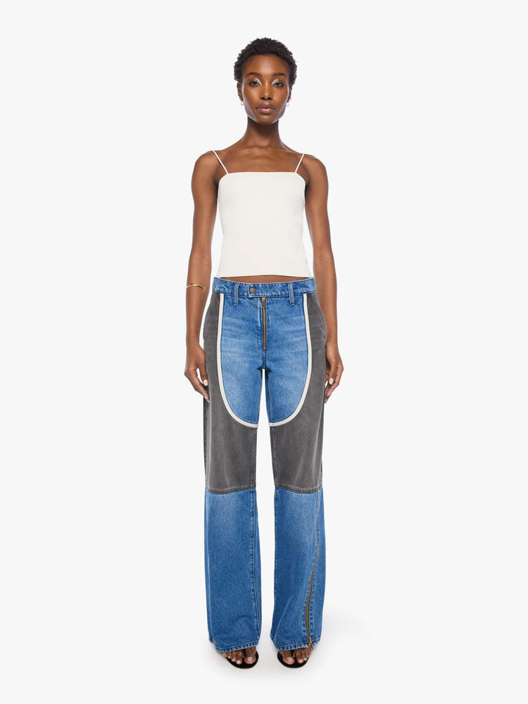 Front view of a woman in mid blue with moto-inspired panels in faded black with white trim at the hips wide-leg jeans are designed with an exposed zip fly, button-tab waistband, side slit pockets, a zipper down the outer calf seam and a long 32-inch inseam with a clean hem.