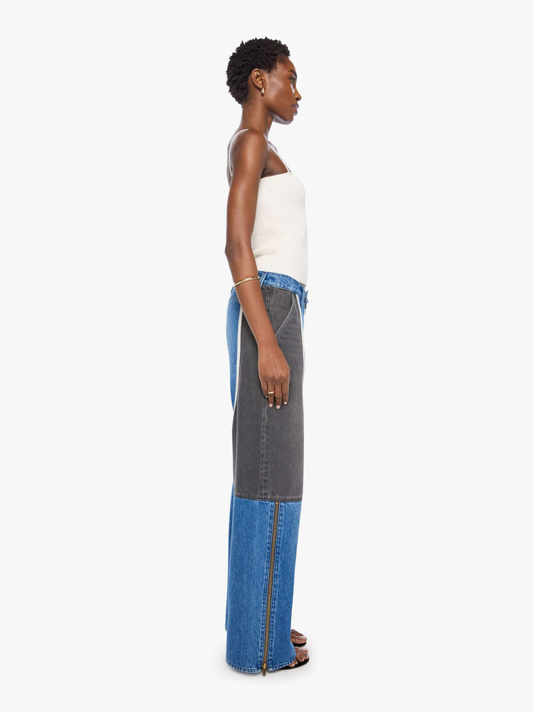 Side view of a woman in mid blue with moto-inspired panels in faded black with white trim at the hips wide-leg jeans are designed with an exposed zip fly, button-tab waistband, side slit pockets, a zipper down the outer calf seam and a long 32-inch inseam with a clean hem.