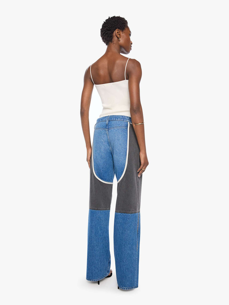 Back view of a woman in mid blue with moto-inspired panels in faded black with white trim at the hips wide-leg jeans are designed with an exposed zip fly, button-tab waistband, side slit pockets, a zipper down the outer calf seam and a long 32-inch inseam with a clean hem.