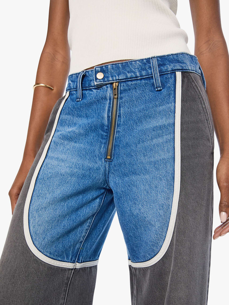 Cloe up view of a woman in mid blue with moto-inspired panels in faded black with white trim at the hips wide-leg jeans are designed with an exposed zip fly, button-tab waistband, side slit pockets, a zipper down the outer calf seam and a long 32-inch inseam with a clean hem.