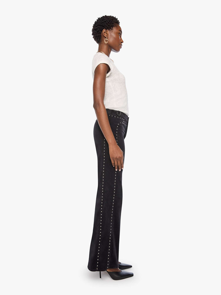 Side view of a woman in a black corduroy high-waisted wide-leg pants with a button fly, adjustable details at the waistband, a 31-inch inseam and clean hem.