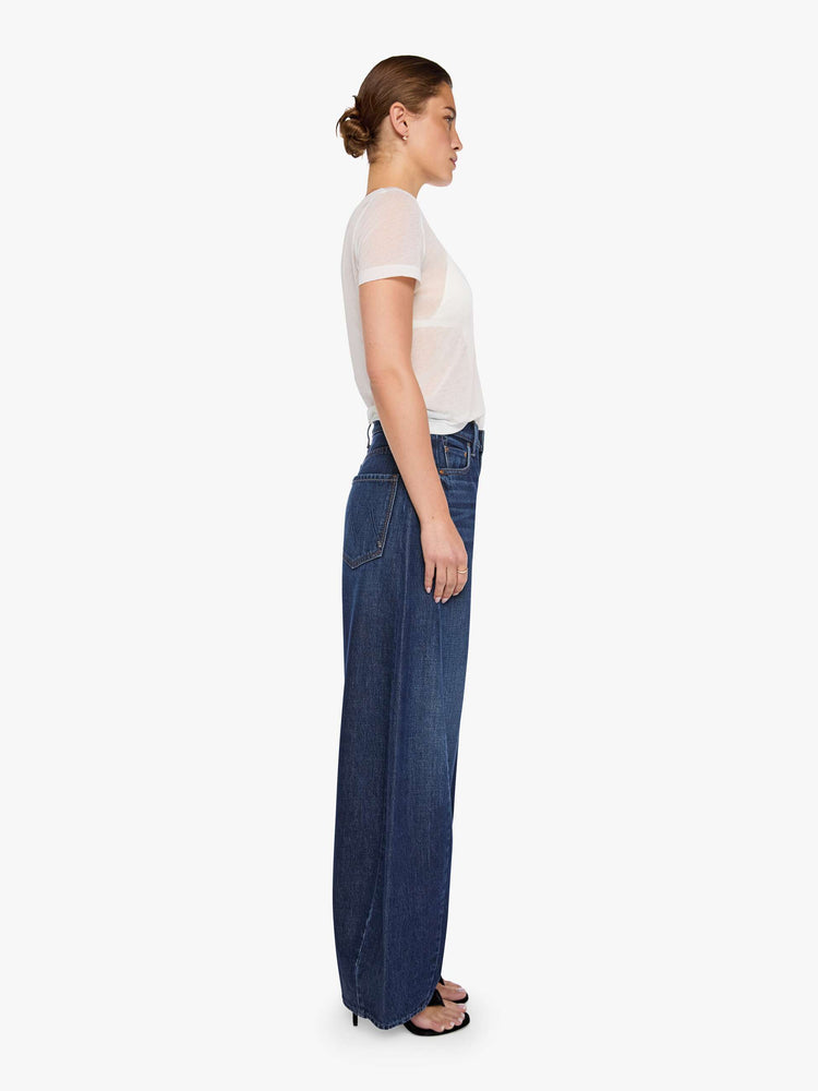 Side view of a woman in a super high-waisted jeans are designed with a zip fly, an inset panel on the outer seam, slightly tapered leg, 30-inch inseam, clean hem and a relaxed fit. 