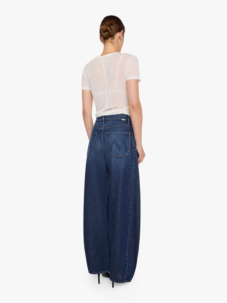 Back view of a woman in a super high-waisted jeans are designed with a zip fly, an inset panel on the outer seam, slightly tapered leg, 30-inch inseam, clean hem and a relaxed fit. 