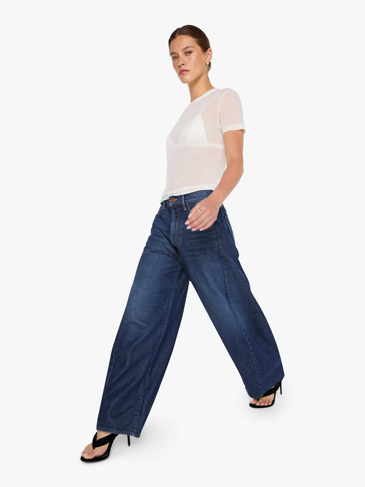 Walking view of a woman in a super high-waisted jeans are designed with a zip fly, an inset panel on the outer seam, slightly tapered leg, 30-inch inseam, clean hem and a relaxed fit. 