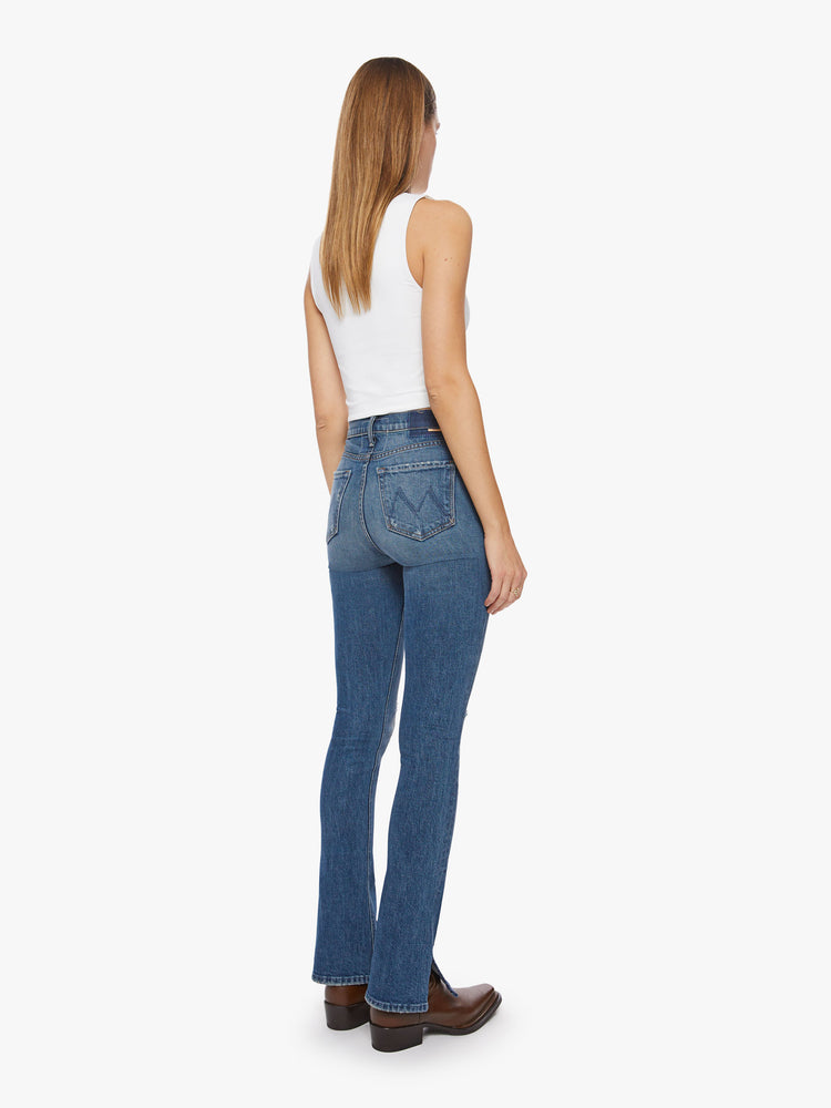 Back view of a classic skinny flare with a high rise and a full-length inseam with a sliced hem in a dark blue wash.