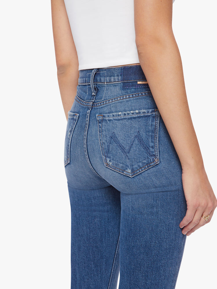 Close up back view of a classic skinny flare with a high rise and a full-length inseam with a sliced hem in a dark blue wash.