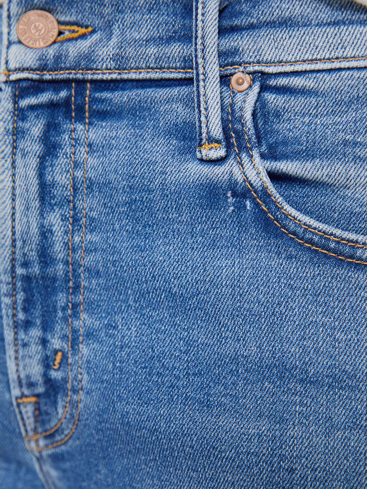 Swatch view of a woman in a med blue mid-rise jeans with a loose fit, wide leg, zip fly and a 31-inch inseam with a frayed hem.