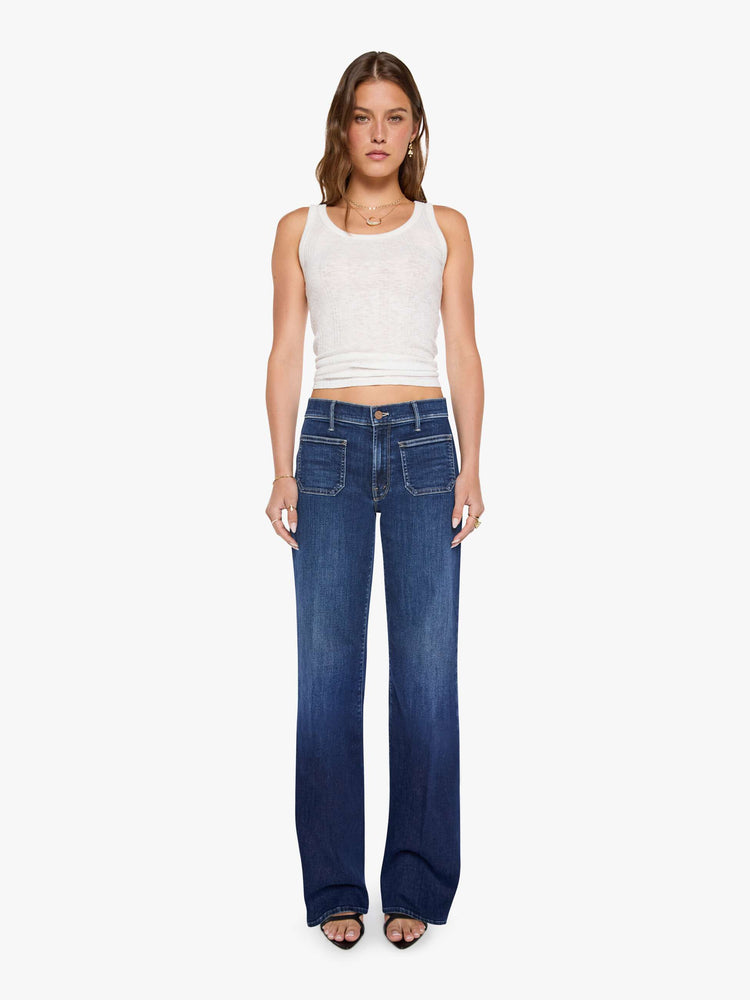 Front view of a woman in a dark blue mid-rise jeans with a loose fit, wide leg, patch pockets, zip fly and 32-inch inseam with a clean hem.