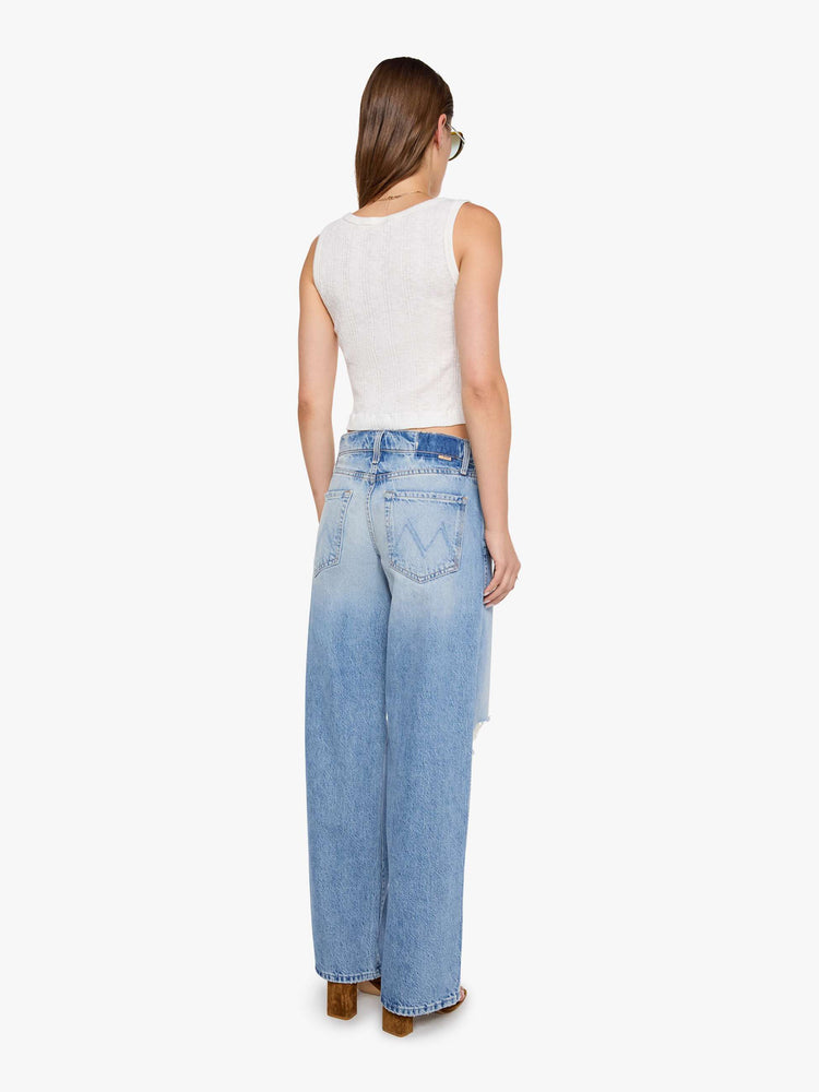 Back view of a woman in a med blue jeans designed to sit lower on the hips with a 32-inch inseam, zip fly, clean hem and slightly tapered leg.