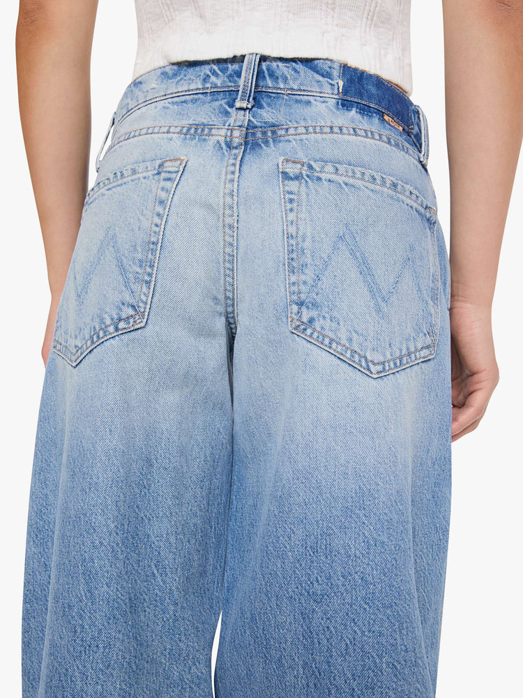 Close up back view of a woman in a med blue jeans designed to sit lower on the hips with a 32-inch inseam, zip fly, clean hem and slightly tapered leg.