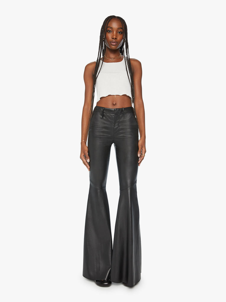 Front view of a woman mid rise pants with diagonal seams at the knees, a super-wide flare and an extra-long 35-inch inseam in a faux black leather.