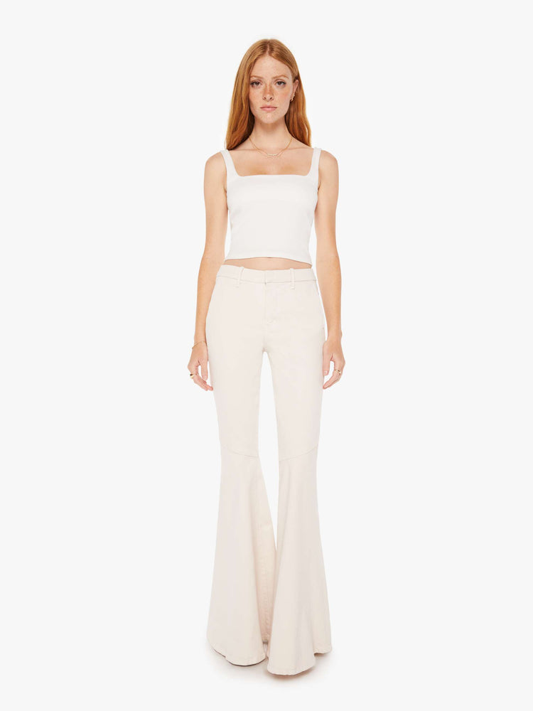 Front view of a woman high-rise pants with diagonal seams at the knees, a super-wide flare, slit pockets and an extra-long 35-inch inseam in a light khaki cream.