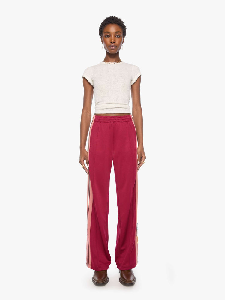 Front view of a woman in an athletic-inspired pants with an elastic waistband, side slit pockets, a loose straight leg and snaps down the outer seams.