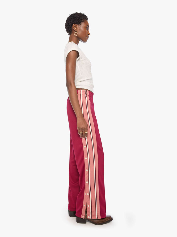 Side view of a woman in an athletic-inspired pants with an elastic waistband, side slit pockets, a loose straight leg and snaps down the outer seams.