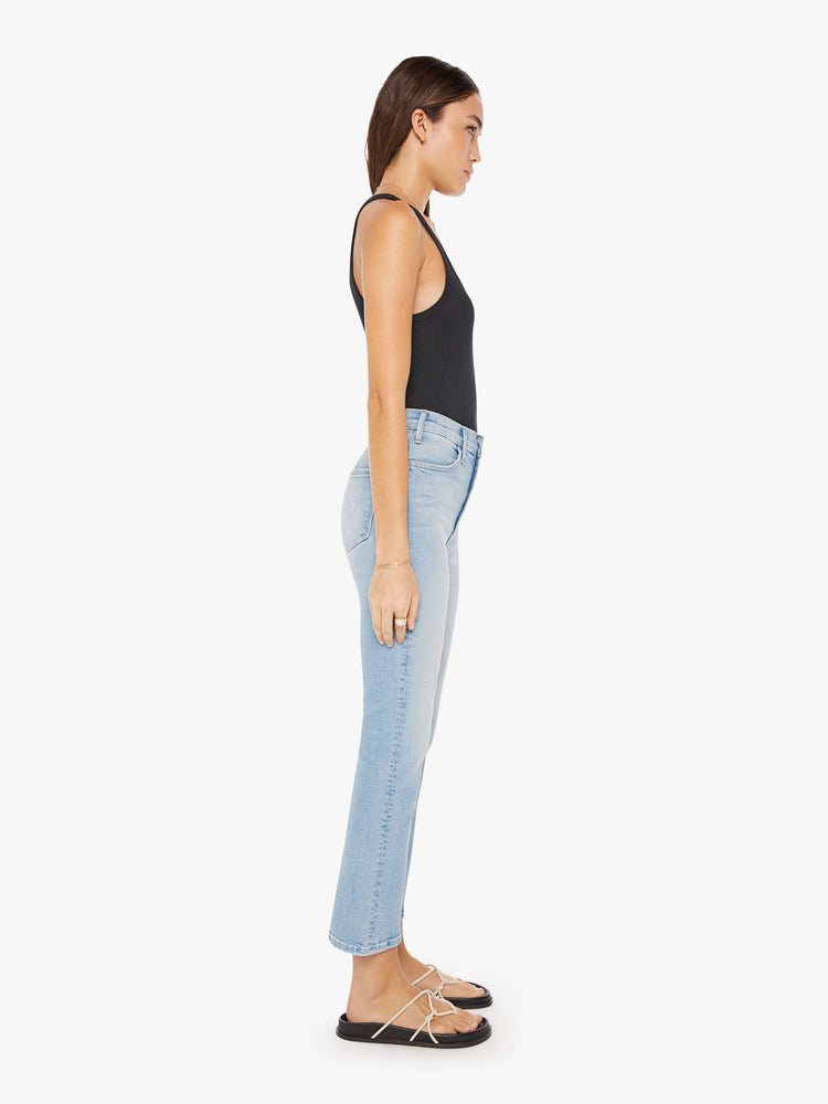 Side view of a womens light blue wash jean featuring a high rise and an ankle length flare with a clean hem.