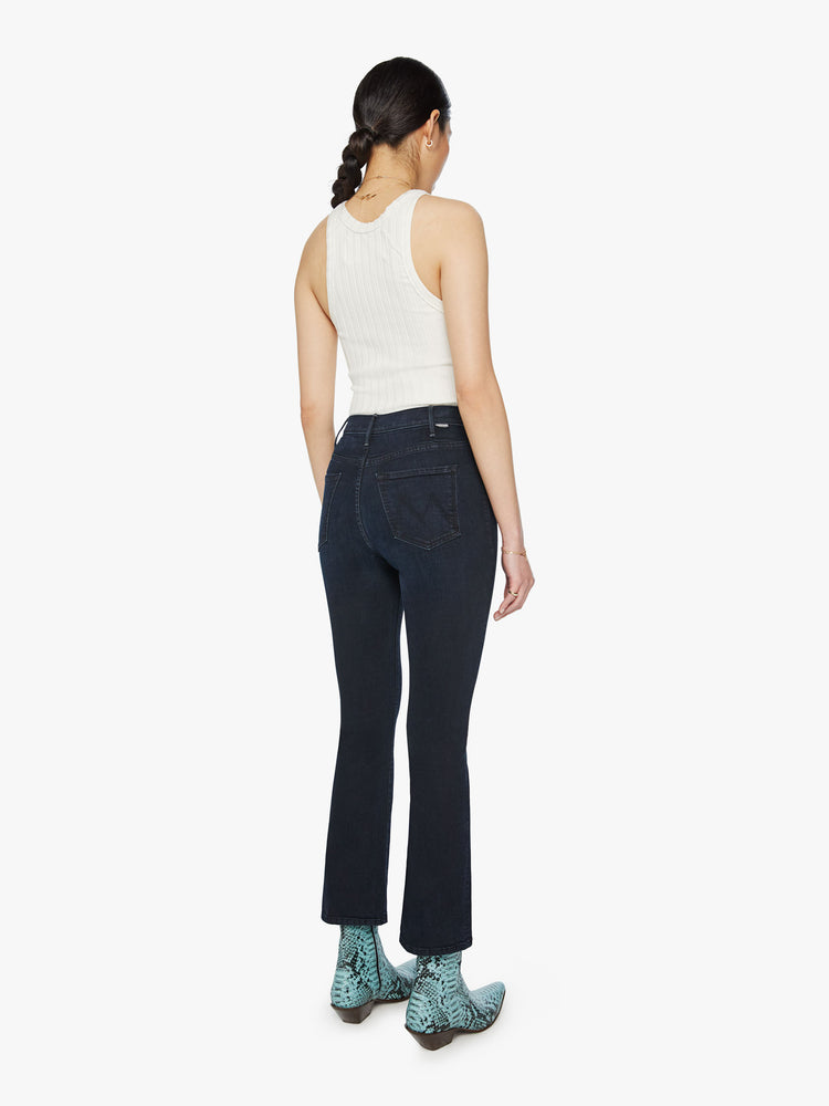 Back view of a woman high-rise flare with an ankle-length inseam and a clean hem in dark blue wash.