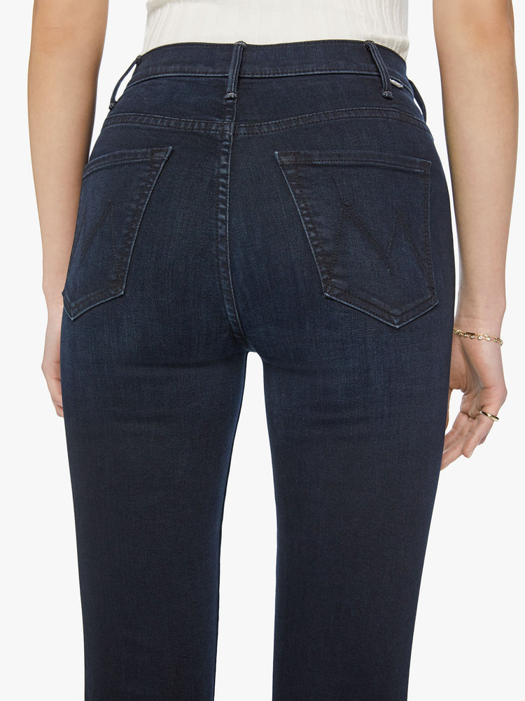 Back close up view of a woman high-rise flare with an ankle-length inseam and a clean hem in dark blue wash.