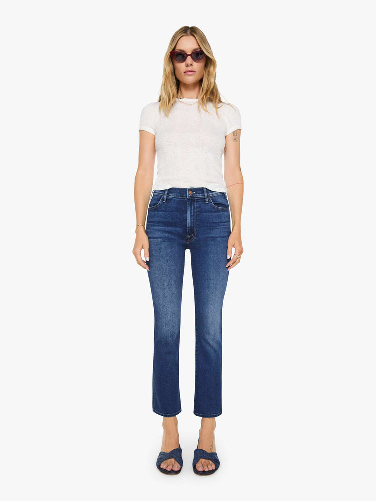 Front view of a woman in a dark blue high-rise flare jean with an ankle-length inseam and a clean hem.