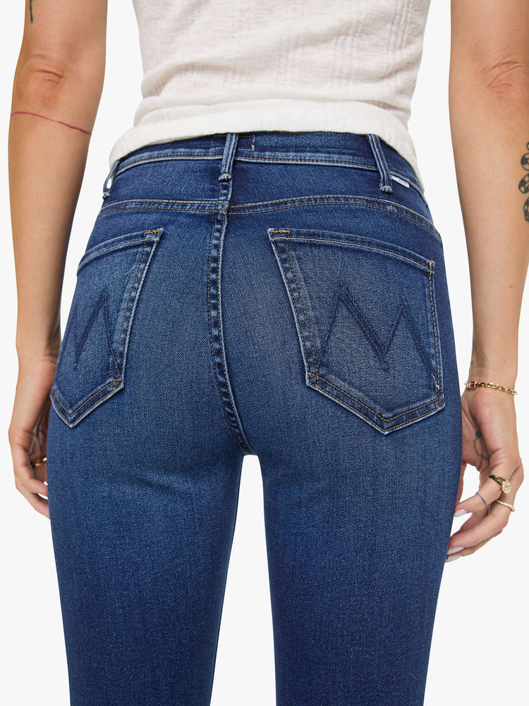 Close up view of a woman in a dark blue high-rise flare jean with an ankle-length inseam and a clean hem.