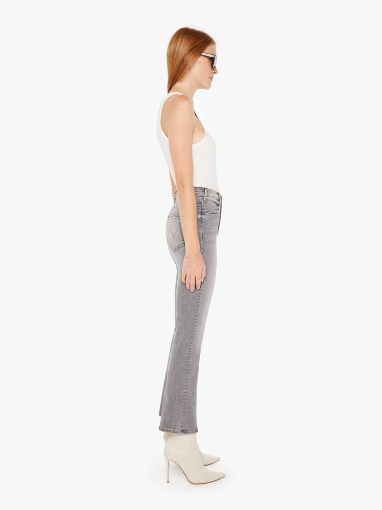 Side view of a womens grey wash jean featuring a high rise and an ankle length flare leg.