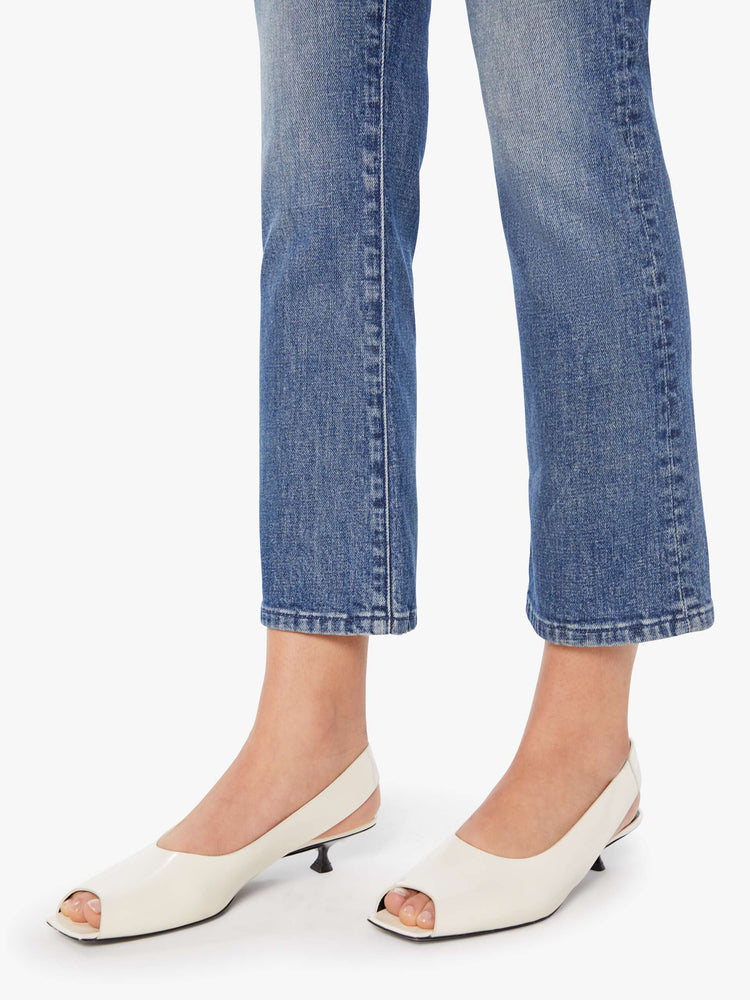 Hem view of a woman in a mid-blue high-rise flare has a zip fly, ankle-length inseam and a clean hem.