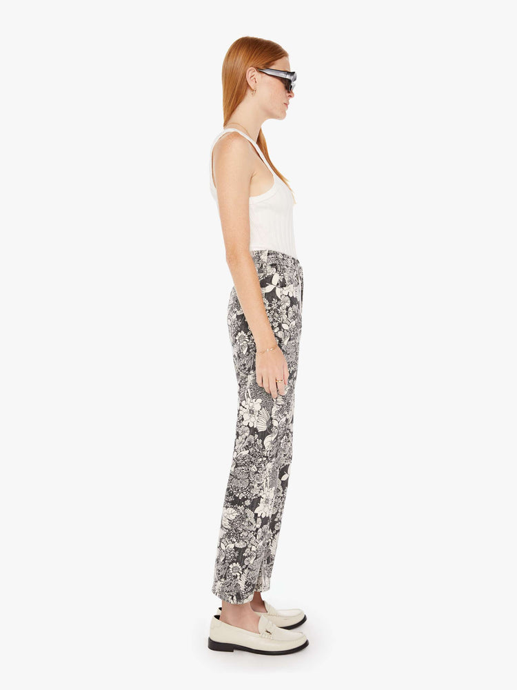 Side view of a womens high rise flare jean featuring an all over black and white print of flowers.