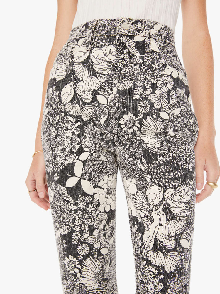 Front close up view of a womens high rise flare jean featuring an all over black and white print of flowers.
