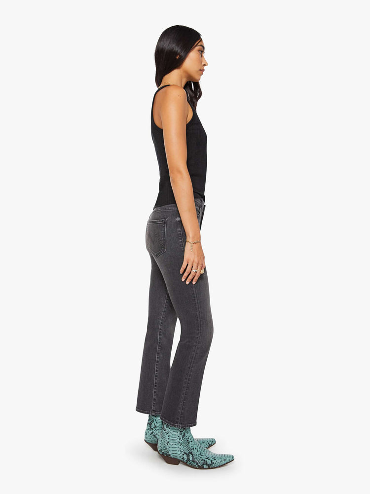 Side view of a woman in a faded grey high-rise flare has an ankle-length inseam and a clean hem.