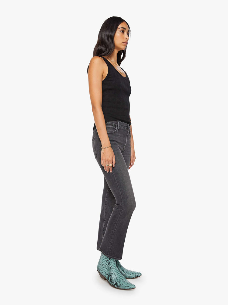 Side angle view of a woman in a faded grey high-rise flare has an ankle-length inseam and a clean hem.