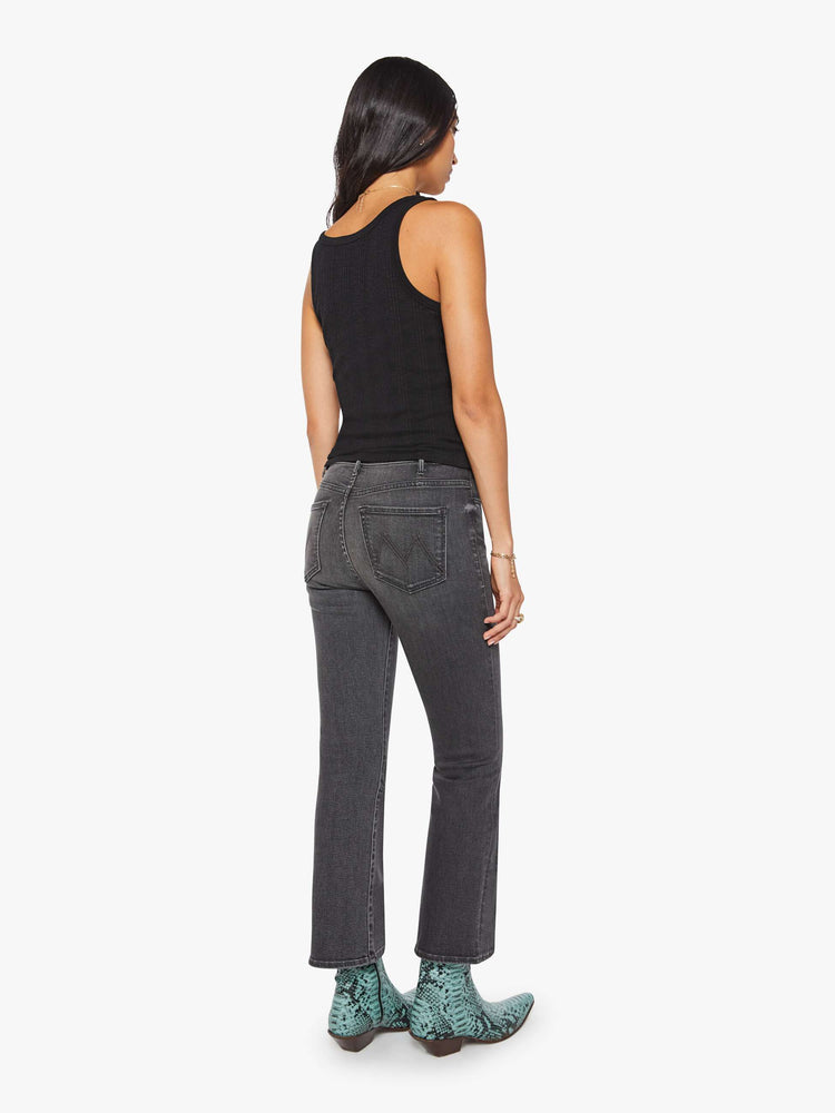 Back view of a woman in a faded grey high-rise flare has an ankle-length inseam and a clean hem.