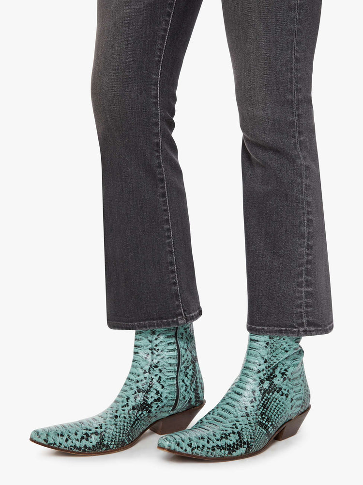 Hem close up view of a woman in a faded grey high-rise flare has an ankle-length inseam and a clean hem.