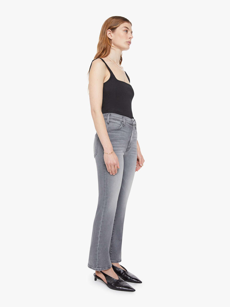 Side angle view of a woman in a grey high-rise flare has a zip fly, ankle-length inseam and a clean hem.