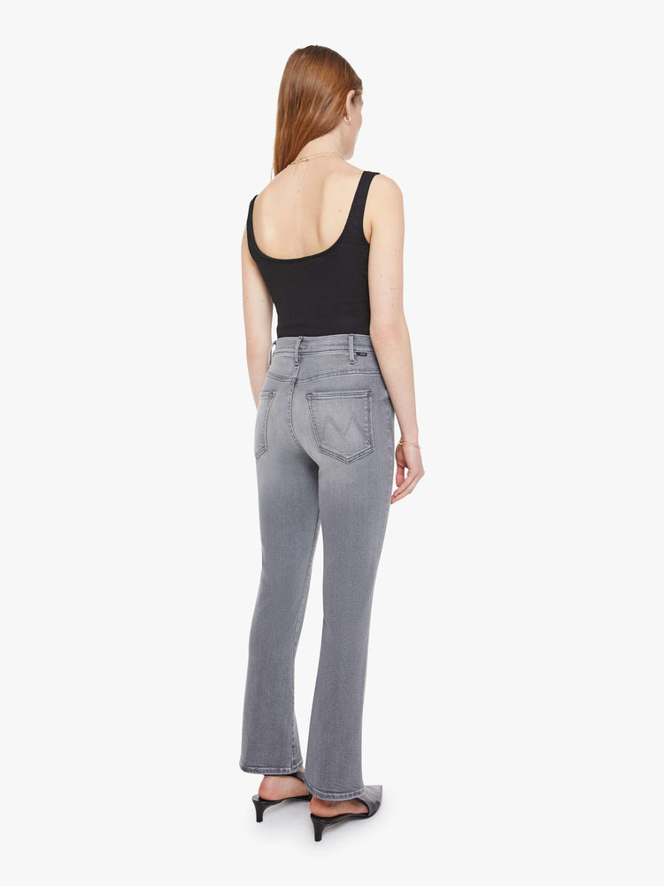 Back view of a woman in a grey high-rise flare has a zip fly, ankle-length inseam and a clean hem.