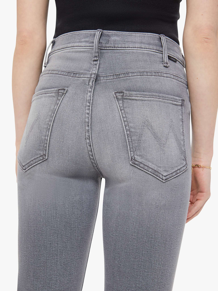 Close up view of a woman in a grey high-rise flare has a zip fly, ankle-length inseam and a clean hem.
