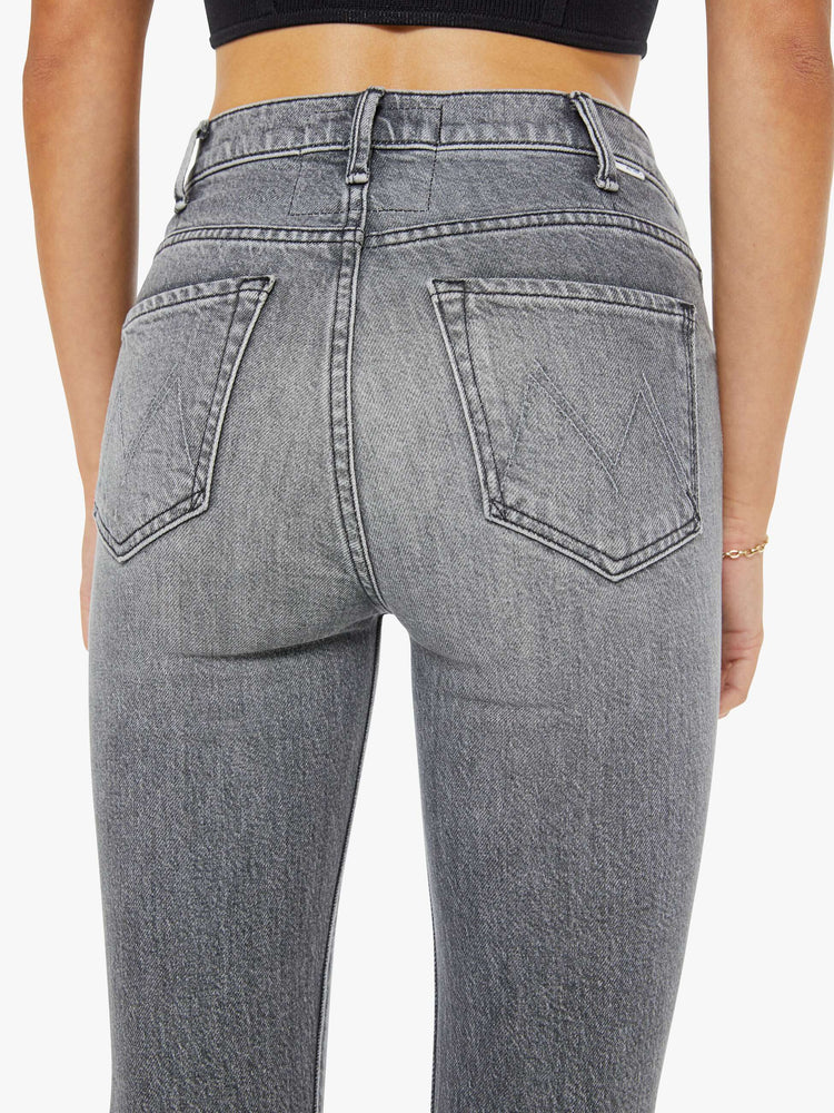 Close up view of a woman in a light grey high-rise flare has a zip fly, ankle-length inseam and a clean hem.