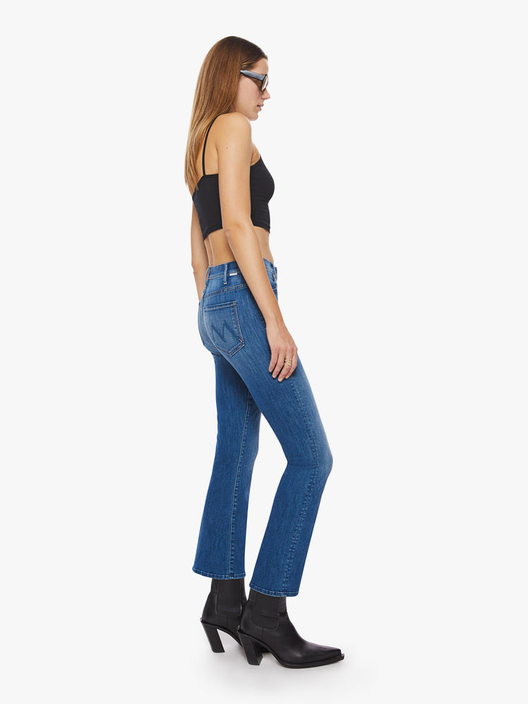 Side view of a woman mid blue high-rise skinny-flare has an ankle-length inseam and a clean hem.