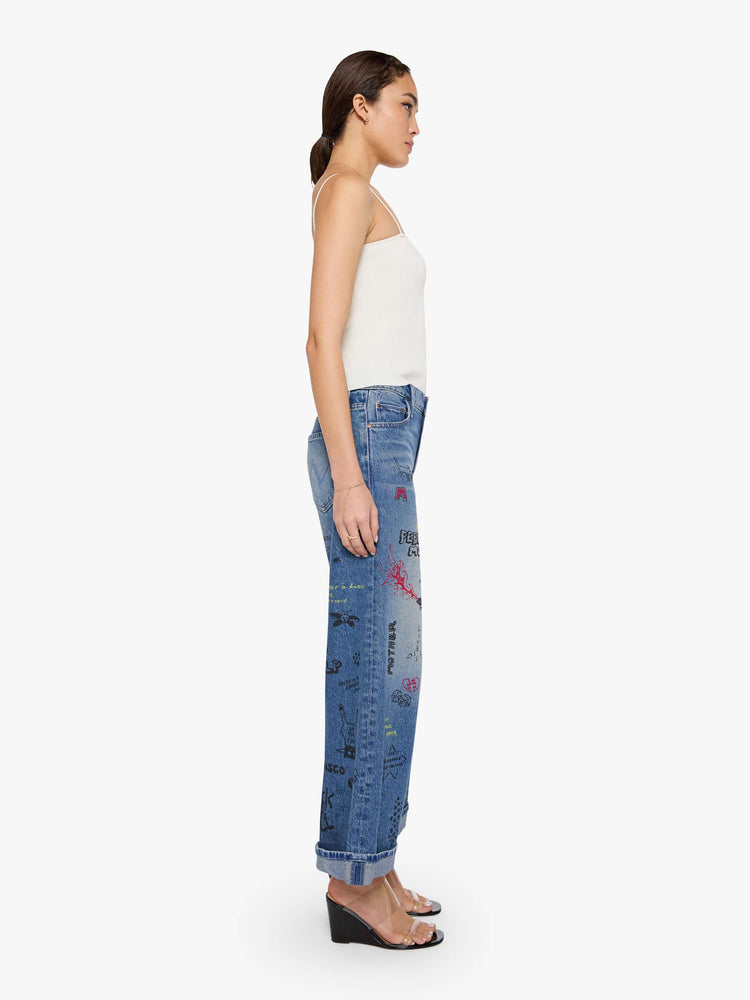 Side view of a woman in a wide-leg jeans are designed with a zip fly, low slung fit and a 28.25-inch inseam with a cuffed hem.
