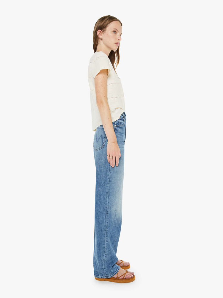 Side view of a woman in a med blue super high-waisted wide-leg jeans with a zip fly, long 32-inch inseam and a clean hem.