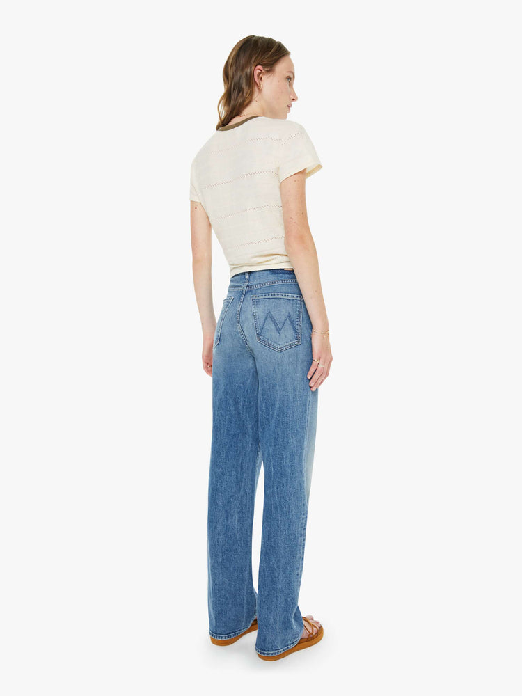 Back view of a woman in a med blue super high-waisted wide-leg jeans with a zip fly, long 32-inch inseam and a clean hem.
