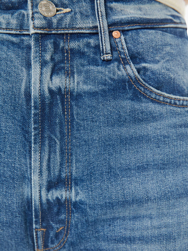 Close up view of a woman in a med blue super high-waisted wide-leg jeans with a zip fly, long 32-inch inseam and a clean hem.