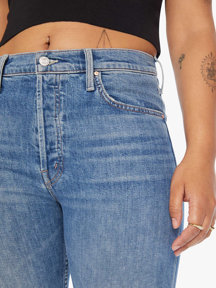 Front close up view of a womens medium blue wash jean featuring a high rise, straight leg.