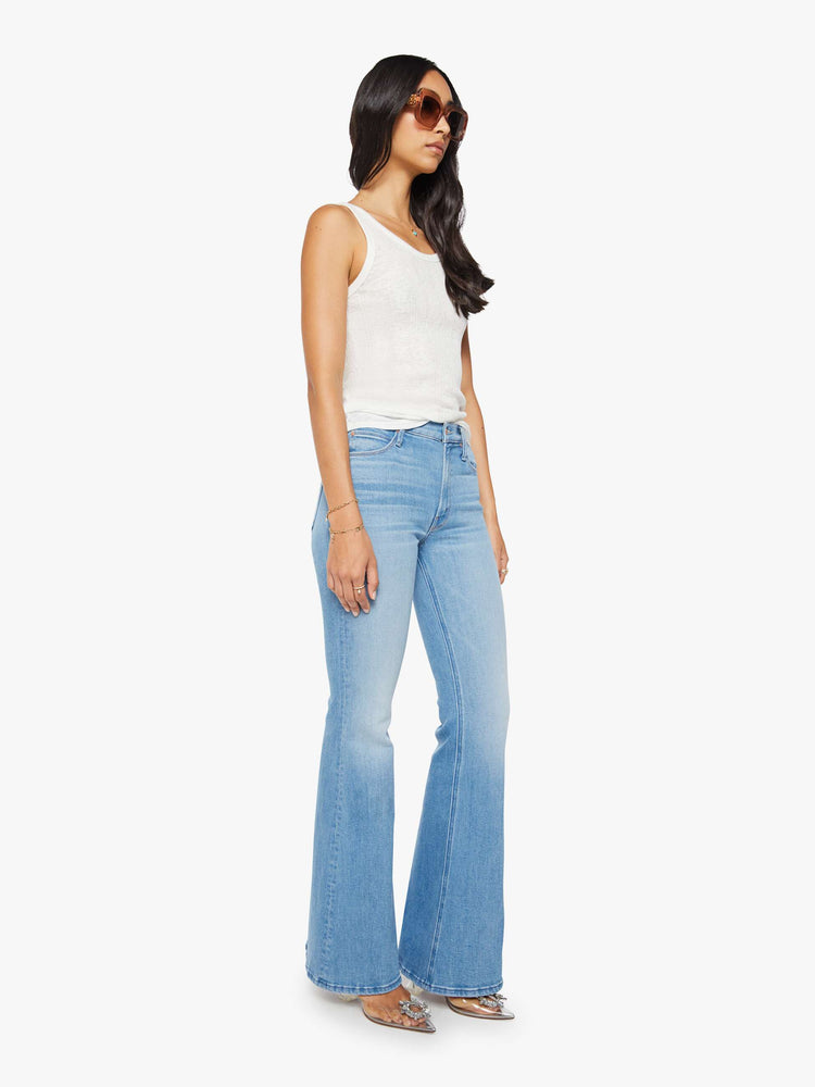 Side angle view of a woman in a light blue high-rise flare with a zip fly, long 34-inch inseam and a clean hem.