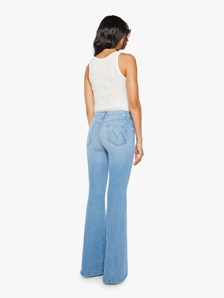 Back view of a woman in a light blue high-rise flare with a zip fly, long 34-inch inseam and a clean hem.