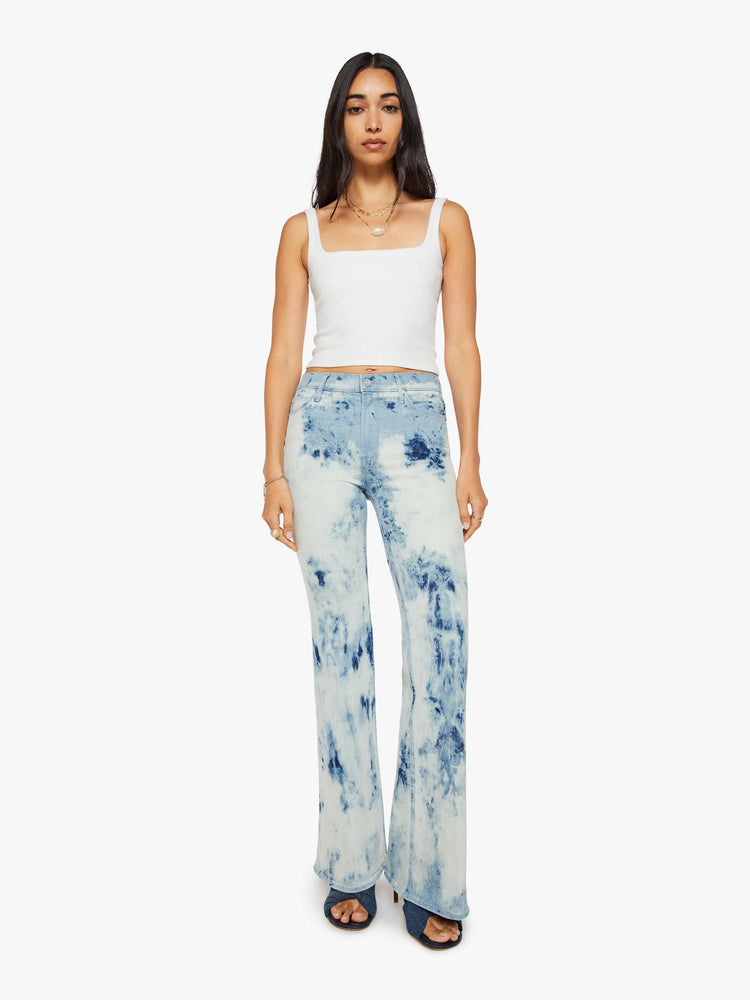 Front view of a woman in a bleach-dyed light blue with darker and lighter spots throughout high-rise flare jean with a zip fly, long 34-inch inseam and a clean hem. 
