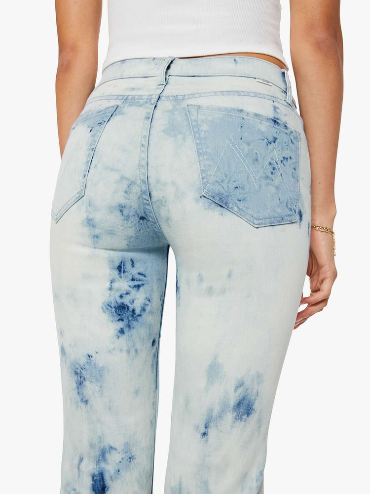 Back close up view of a woman in a bleach-dyed light blue with darker and lighter spots throughout high-rise flare jean with a zip fly, long 34-inch inseam and a clean hem. 